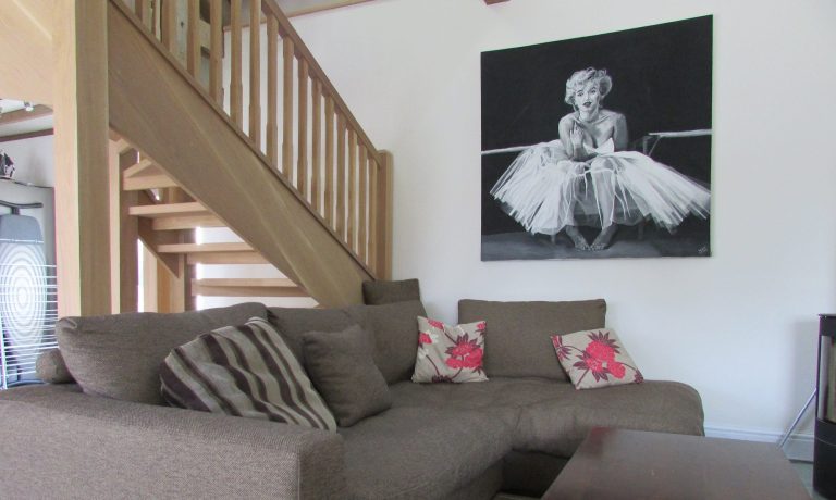 Professionally cleaned modern living room in Llanelli with grey sofa and wooden staircase